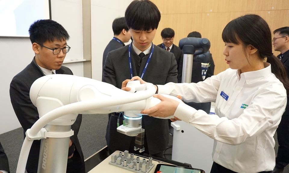 두산로보틱스 본사(경기도 수원)에서 열린 로봇 아카데미에 참가한 삼일공업고등학교 학생들이 두산로보틱스 연구원들과 함께 협동로봇을 시연하고 있다.
