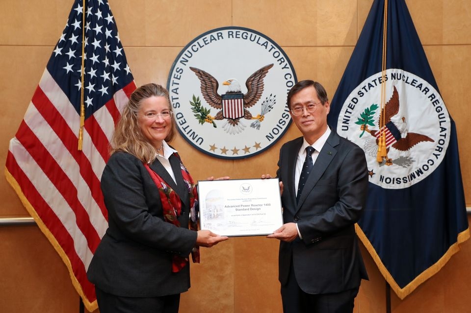 26일(현지시간) 워싱턴D.C. 미국 원자력규제위원회(NRC) 본부에서 열린 인증서 수여식 행사에서 정재훈 한수원 사장(오른쪽)이 NRC 위원(Annie Caputo)으로부터 인증서를 받고 있다.