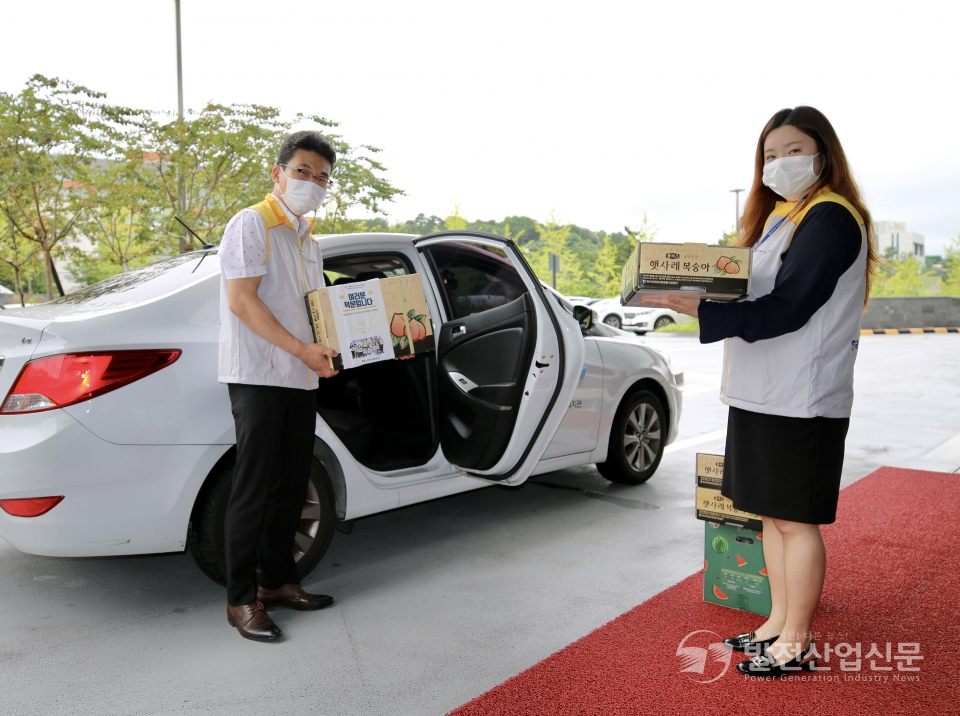 한국동서발전(주) 직원들이 사회복지기관에 전달할 과일을 싣고 있는 모습.