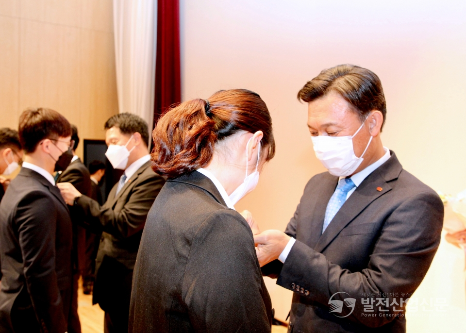 김영문 한국동서발전 사장(주)(오른쪽)이 신입사원에게 휘장을 달아주는 모습.